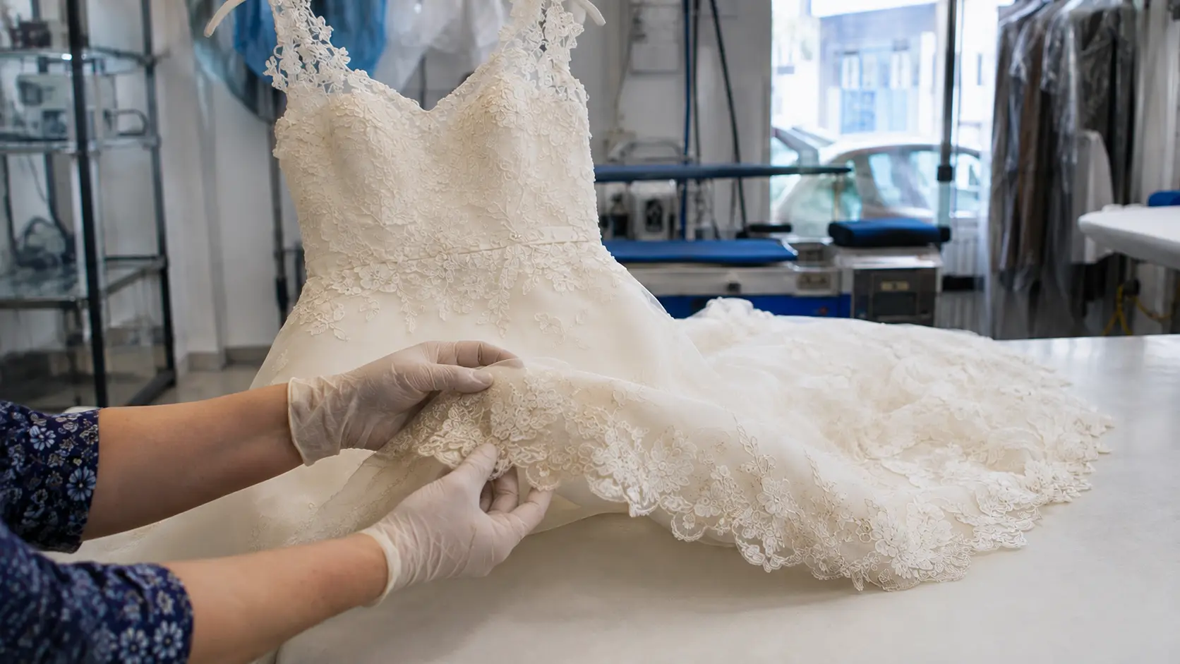 Operaria revisando el encaje y el bajo de un vestido de novia en una tintorería de Lorca